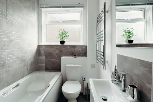 a bathroom with a tub and a toilet and a sink at K Suites - Station Road 13 in Hinckley