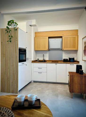a kitchen with white cabinets and a table with cups on it at In the nature in Vroutek