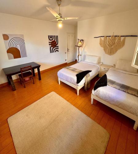 a bedroom with two beds and a table and a rug at Villa Maadi 35 - R 205- Pool View Room in Cairo