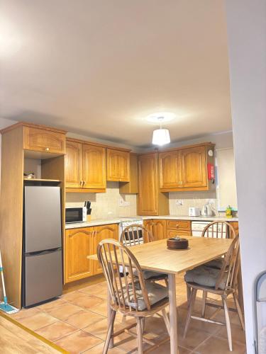 a kitchen with wooden cabinets and a table and chairs at Cobh Panorama- Sea & Cathedral Views in Cobh