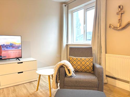 a living room with a chair and a tv at Cobh Panorama- Sea & Cathedral Views in Cobh