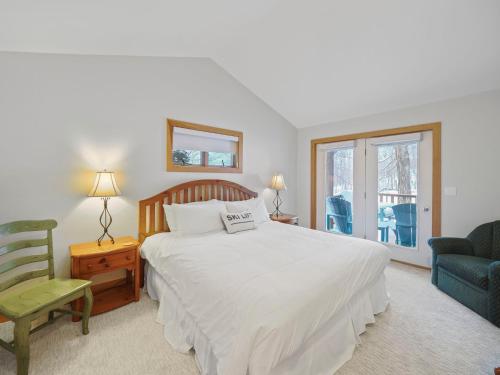 a bedroom with a bed and a chair and a window at 692 Disciples Village Condo in Boyne Falls
