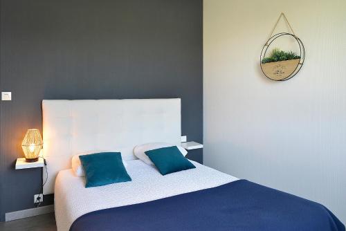 a bedroom with a bed with blue pillows and a mirror at Logis Hôtel Restaurant Berry Relais in Neuvy-Pailloux