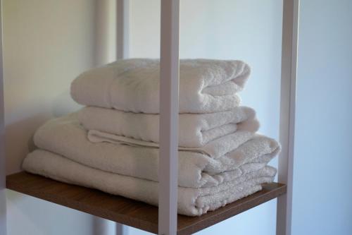 a stack of white towels on a wooden shelf at Casa Rural Lugar Vista Alegre in Lugo