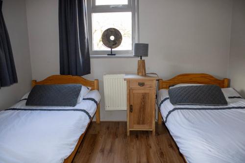 two twin beds in a room with a window at Oes-Tilber in Zweeloo