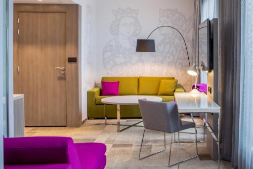 a living room with a yellow couch and a table at Mercure Krakow Stare Miasto in Kraków
