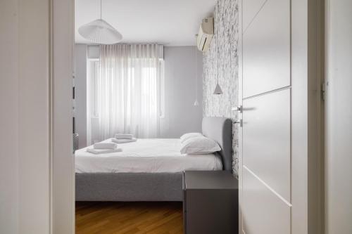 a small white bedroom with a bed and a window at Assago Forum Apt - 3 min Walk in Assago