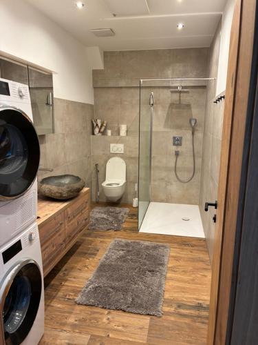 a bathroom with a shower and a toilet and a washing machine at Ferienhaus Wieswald in Ehrwald