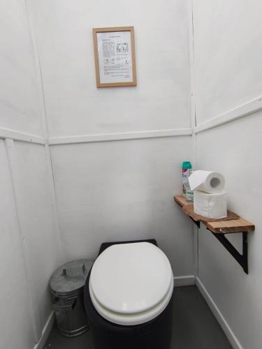 a small bathroom with a white toilet and a shelf at Fitz Roy Comfort Camp - El Chaltén in El Chalten