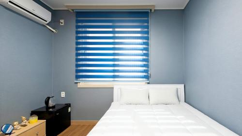 a bedroom with a white bed and a window at Yeosu Trip Pension in Yeosu
