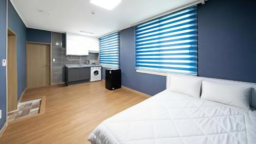 a bedroom with a white bed and a kitchen at Yeosu Trip Pension in Yeosu