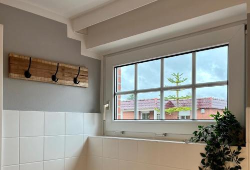 a bathroom with a bath tub and a window at Ferienhaus Kompassqualle in Dornumersiel