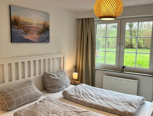 a bedroom with a bed and two windows at Ferienhaus Kompassqualle in Dornumersiel