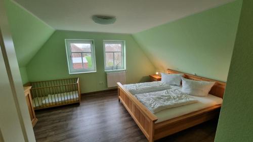 a bedroom with a bed and two windows at Ferienhaus Sommerwind in Neßmersiel