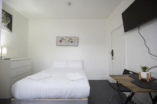a white bedroom with a bed and a desk at Hayy Studios Blackhouse in Huddersfield