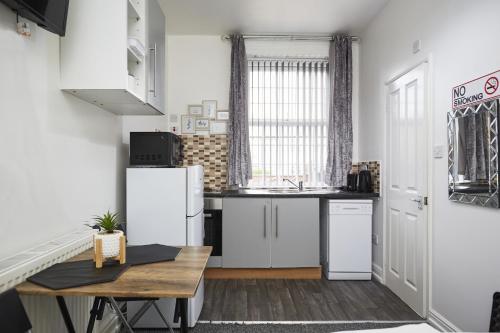 a kitchen with white appliances and a wooden table at Hayy Studios Blackhouse in Huddersfield