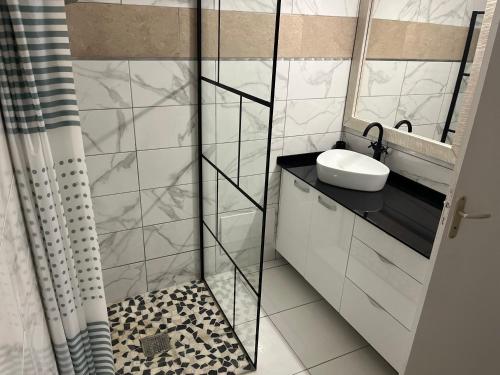 a white bathroom with a sink and a mirror at Milles Eclats in Les Anses-dʼArlets