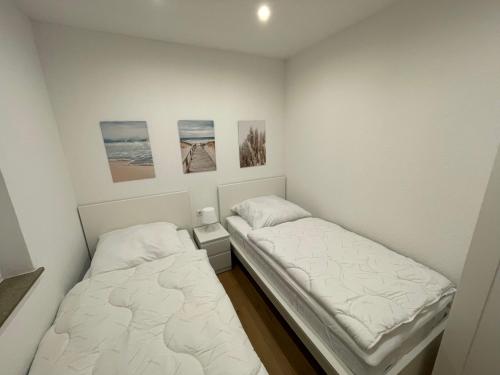 two beds in a small room with paintings on the wall at Ferienhaus Margarete in Dornumersiel