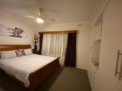 a bedroom with a bed and a ceiling fan at Private 3Bed Home with Large Deck Central Location in Eaglehawk