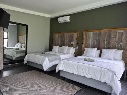 a bedroom with two beds and a mirror at Febe-Mari Guesthouse in Zeerust