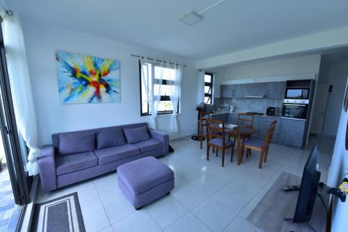 a living room with a couch and a table and a kitchen at Hyacinth Golf& Sea in Grand-Baie