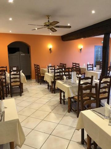 a dining room with tables and chairs and a ceiling at Hôtel Restaurant La Manse in Dornecy