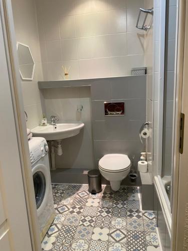 a bathroom with a toilet sink and a washing machine at Apartament 94 Konin in Konin