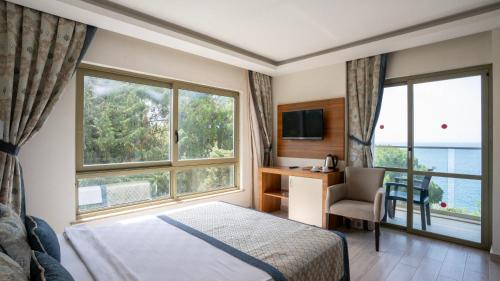 a hotel room with a bed and a desk and windows at İncekum West Hotel -Ultra All Inclusive in Alanya