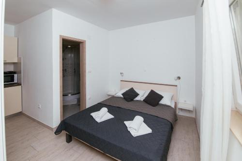 a bedroom with a bed with two white chairs on it at Apartmani AE in Biograd na Moru