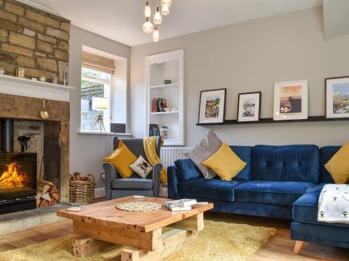 a living room with a blue couch and a fireplace at St Georges Cottage in Holmfirth