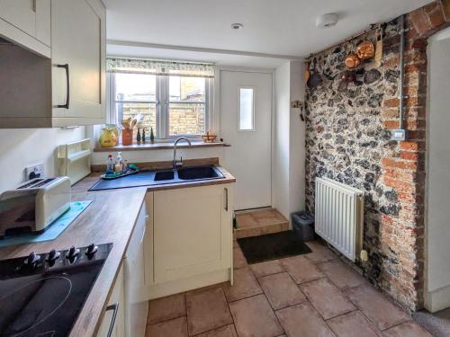 a kitchen with a sink and a brick wall at The Cottage in Broadstairs