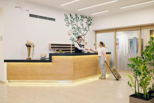 a man and a woman standing at a counter in a lobby at Hotel Park Superior 3* in Čakovec