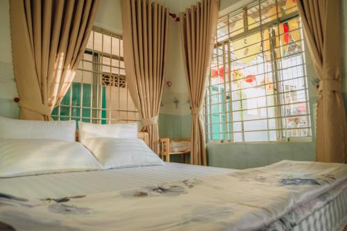 a bedroom with a large bed and windows at Thiện Homestay Dốc Lết -Gần Biển & Nguyên Căn in Ba Ha