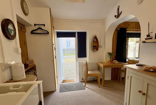 a kitchen with an archway and a table and a door at Meads Cabin in Charmouth
