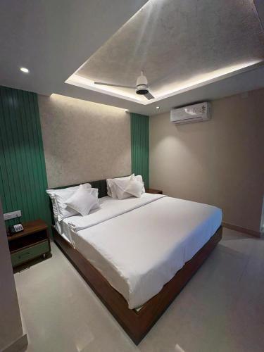 a bedroom with a white bed and a green wall at Majesty inn in Bangalore
