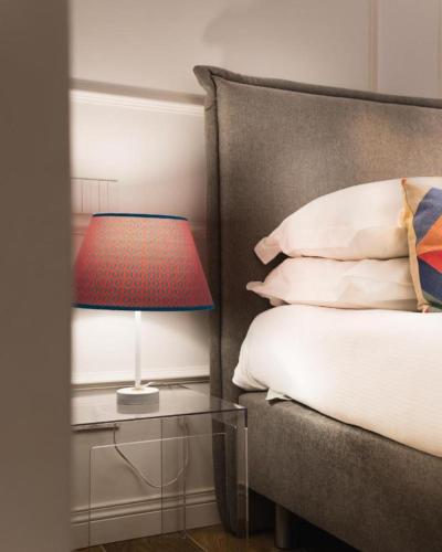 a bed with a red lamp on a glass table at Riviera Suites - by Be Your Home in Civitavecchia