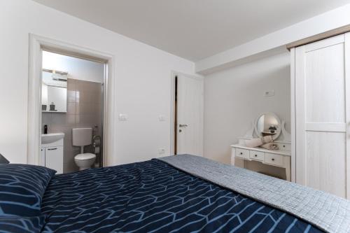a bedroom with a blue bed and a bathroom at House Cerovac in Nedeščina