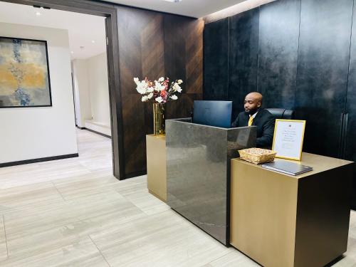 a man sitting at a reception desk in a lobby at 37GS Residences in London