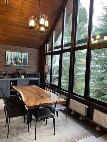 a dining room with a table and chairs and windows at Шале Вершина in Palyanytsya