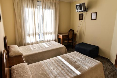 a hotel room with two beds and a chair at Casa Palomin in Ourense