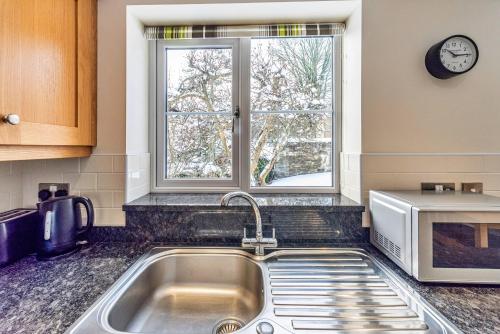 a kitchen counter with a sink and a window at Finest Retreats - Cedar Tree Cottage in Clocaenog
