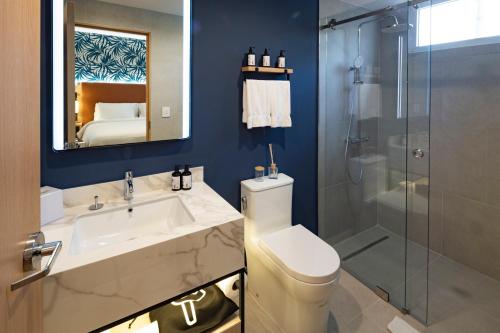 a bathroom with a toilet and a sink and a shower at voco Surfside Aruba by IHG in Oranjestad