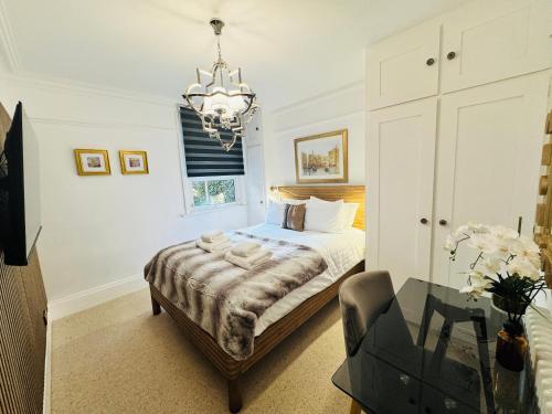 a bedroom with a bed and a chandelier at Luxury Designer 2-Bedroom Apartment with Private Garden & Free Parking in Bexleyheath