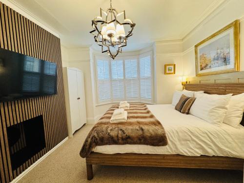 a bedroom with a large bed and a chandelier at Luxury 2 Bed Designer Apartment & Garden in Bexleyheath