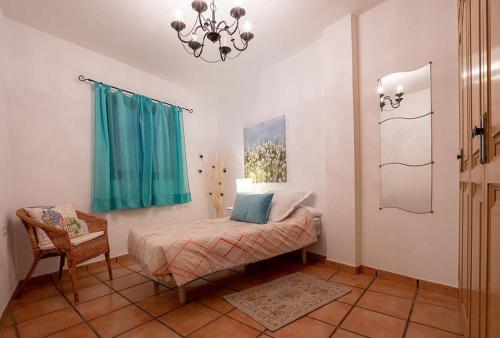 a bedroom with a bed and a chair and a chandelier at Apartamento Vulcano in Adeje