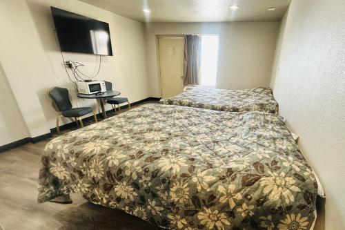 a bedroom with a bed and a desk and a television at The Queen B Motel, Detroit-Warren in Warren