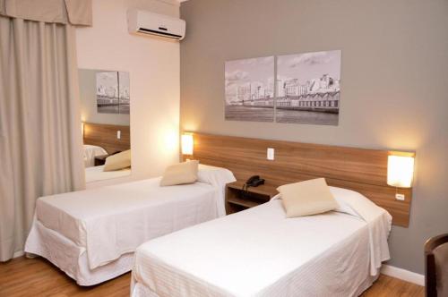 a hotel room with two beds and a mirror at Hotel Açores Premium- 5 minutos do Moinhos de Vento in Porto Alegre