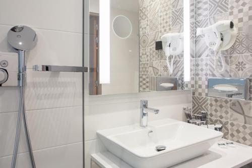 a white bathroom with a sink and a mirror at Mercure Krakow Stare Miasto in Kraków