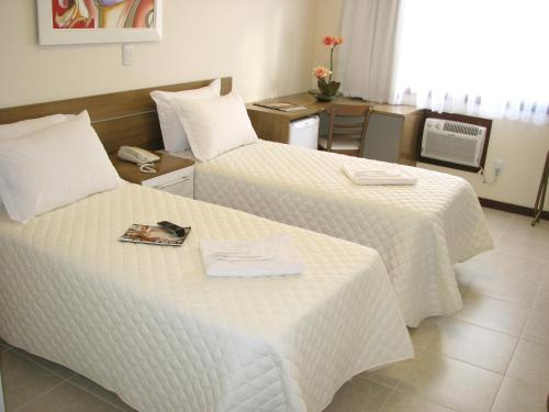 a hotel room with two beds with a magazine on it at Hotel Recanto do Imperador in Rio Pardo
