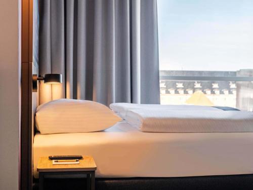 a bed in a hotel room with a window at B&B HOTEL Kassel-Wilhelmshöhe in Kassel